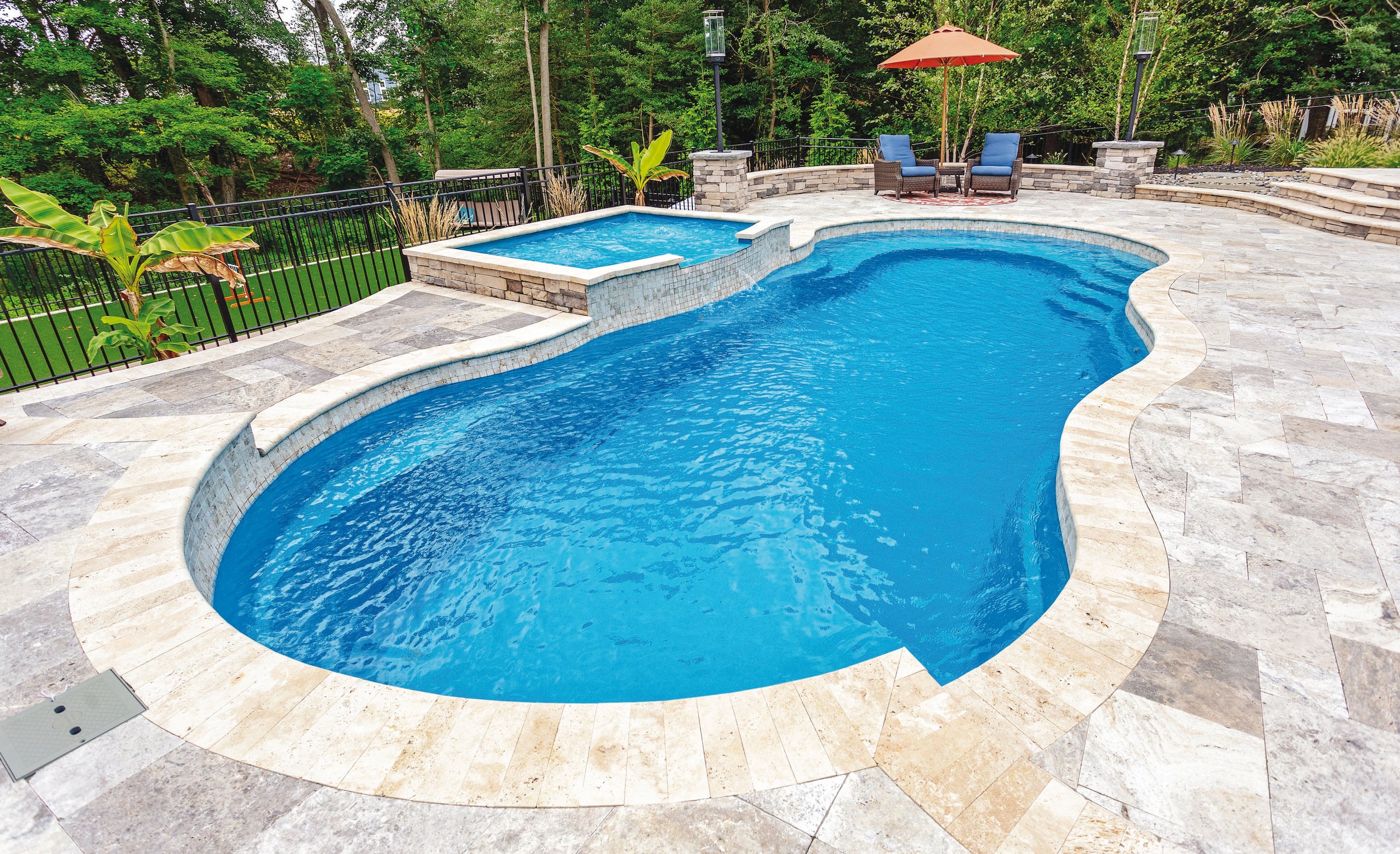 Backyard in-ground swimming pool with patio and landscaping.